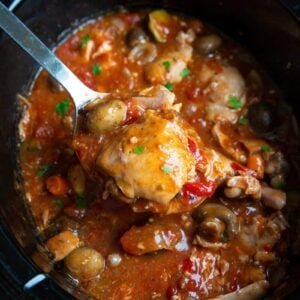 a piece of chicken in a Crockpot with a thick, rich tomato based sauce with lots of vegetables