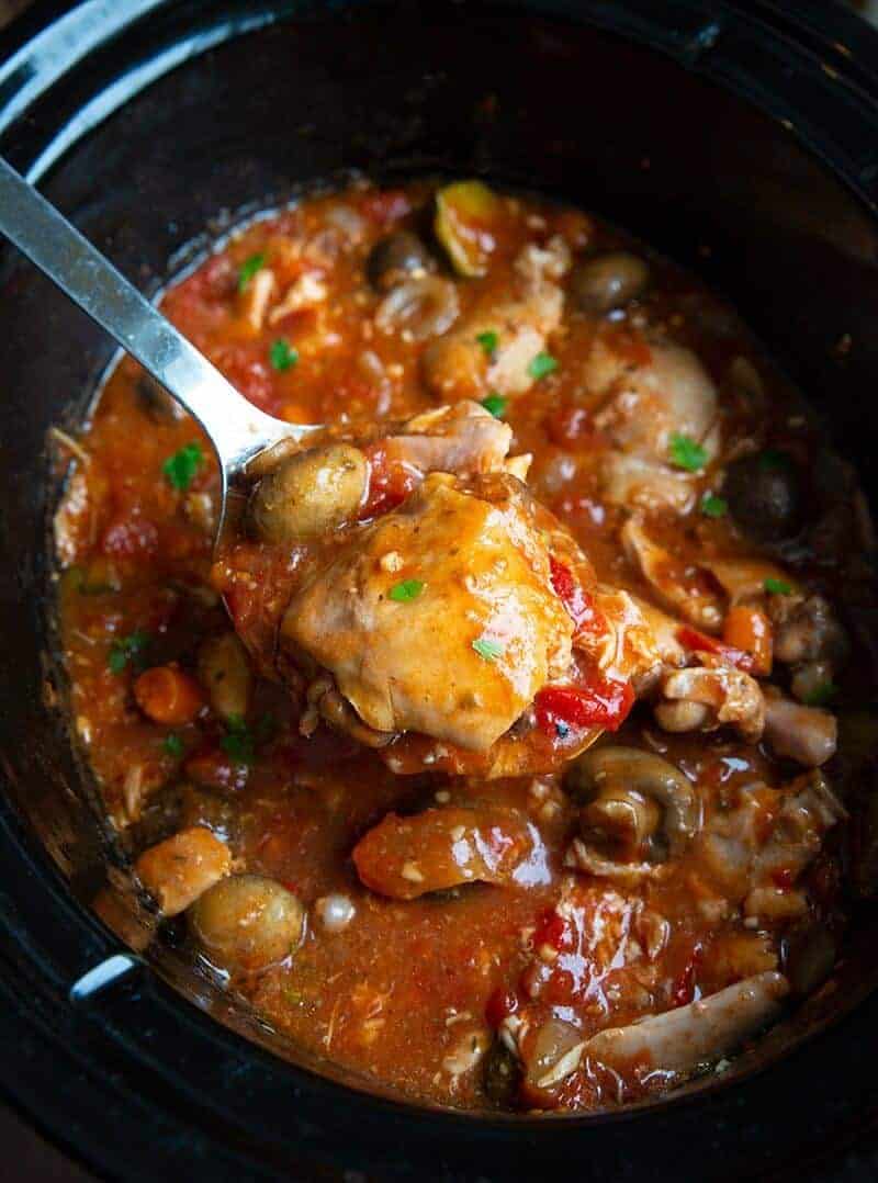 a piece of chicken in a Crockpot with a thick, rich tomato based sauce with lots of vegetables