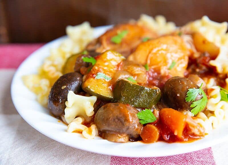 close up Chicken Cacciatore over pasta in a white plate