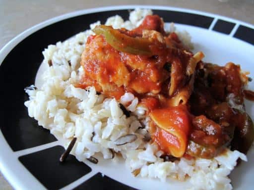 Chicken cacciatore on top of rice in a plate