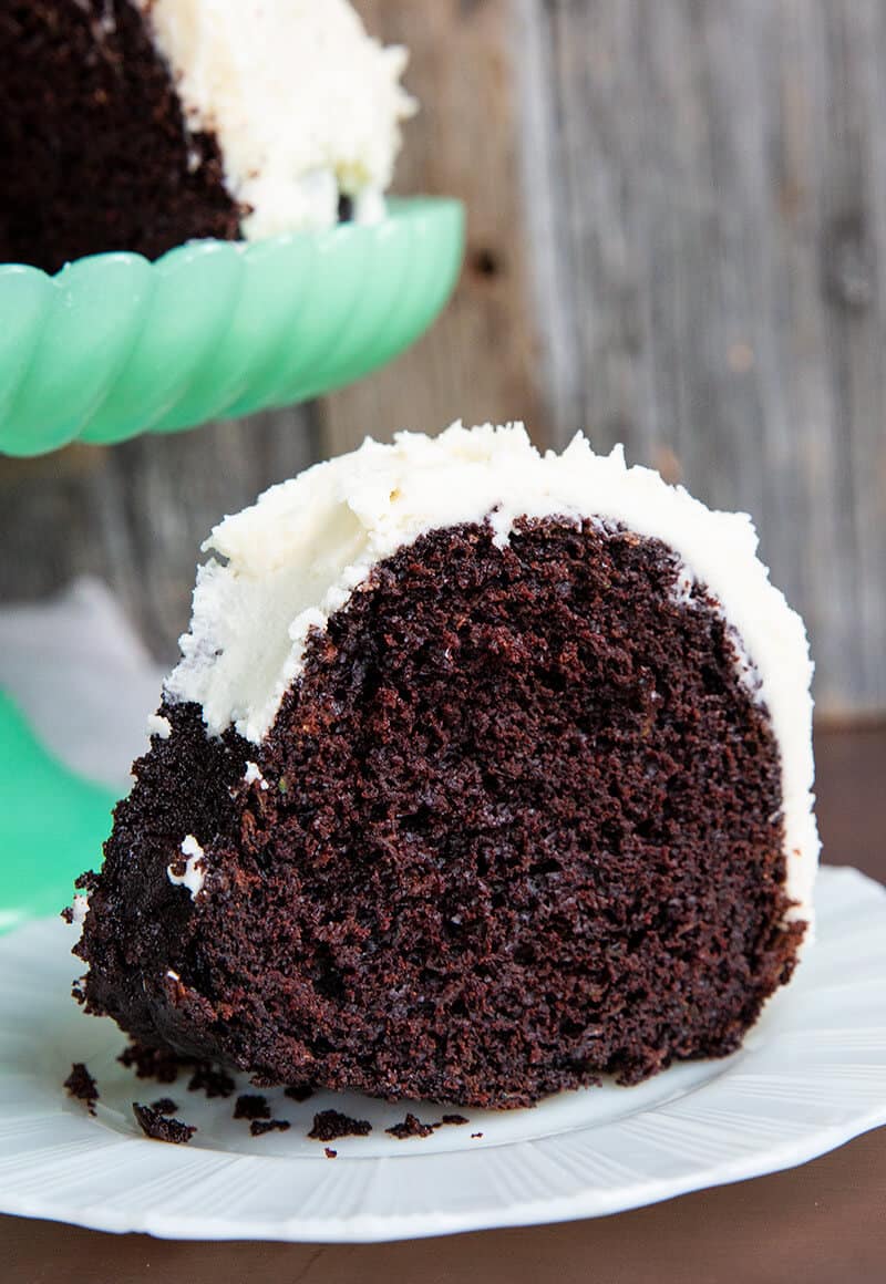 close up of Chocolate Zucchini Cake with white icing in a white dessert plate with fork