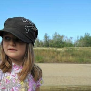 little girl wearing black cap looking sideways