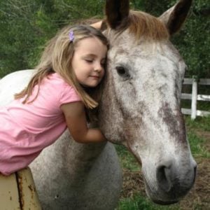 little girl hugging the horse