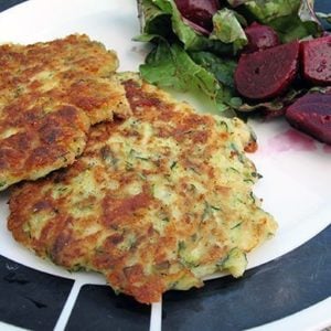 2 pieces Fried Zucchini Cakes in a plate with chunks of beets on side