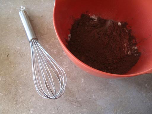 all dry ingredients in a a bowl chocolate and a whisk on side