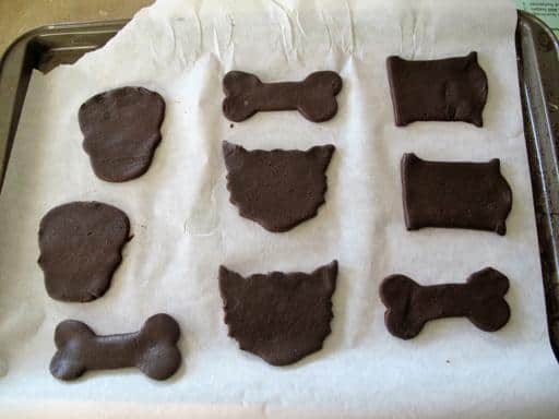 thin dough of chocolate sugar cookies with different shapes in a parchment paper lined baking sheet