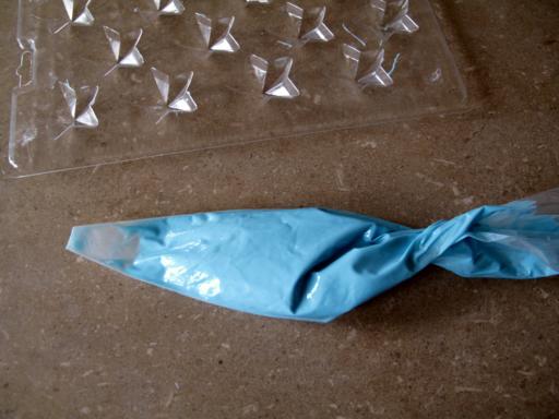 melted blue chocolate disks on plastic bag with end snipped off 