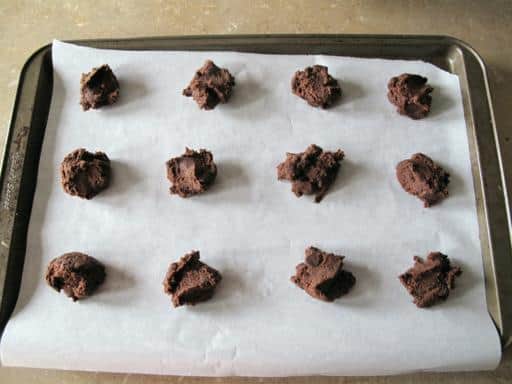 rounded chocolate dough in a parchment lined cookie sheet