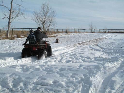 Grandfather and son creating a path in a land covered with snow riding an ATV