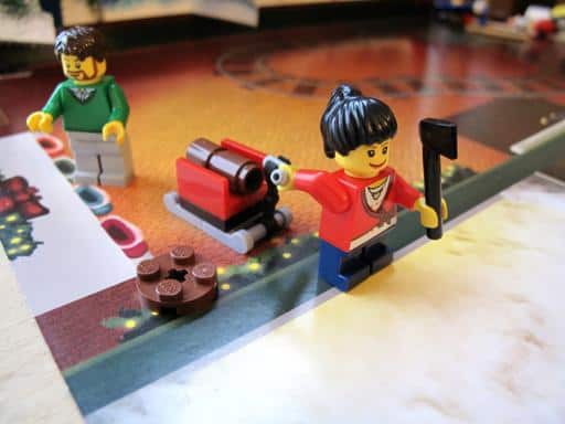 girl lego in red sweater pulling the wagon with wood while holding an axe, guy with the goatee and green sweater at the back