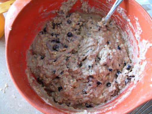 frozen wild blueberries added to Nine Grain Blueberry Muffin mixture in a large red bowl