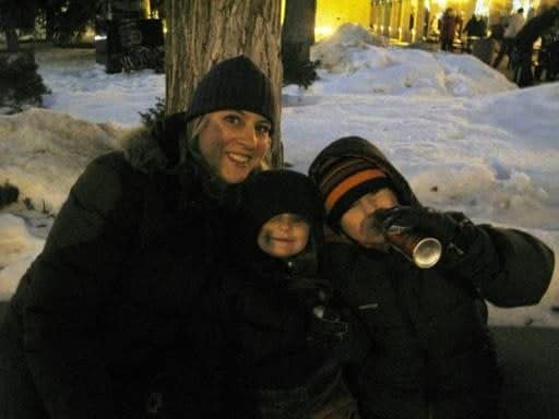 Mom with her two kids sitting in the road filled with snow, one of the kid enjoying his can of coke