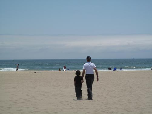 man and little boy, walking towards the ocean hand in hand