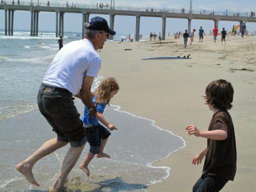 man carrying little girl avoiding the ocean waves on her feet