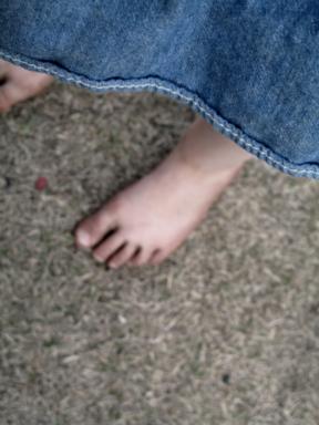close up of dirty feet of a little girl wearing a denim dress