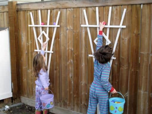 two little kids wearing their jammies reaching for the eggs in the fence