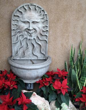 half circle concrete sink in the middle of red poinsettia plants, with a face of sun