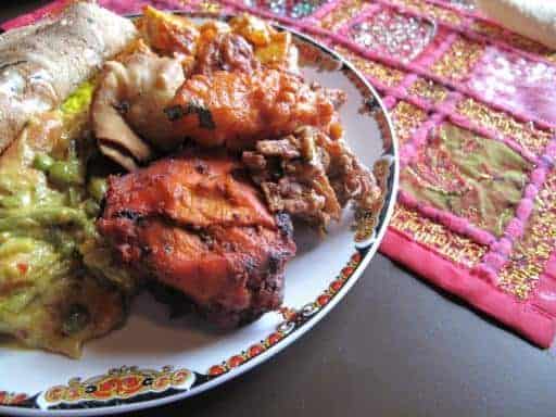 a plate with tandoori chicken, chili chicken and vegetable korm