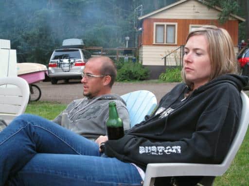 man and woman sitting on a chair outside the cabin