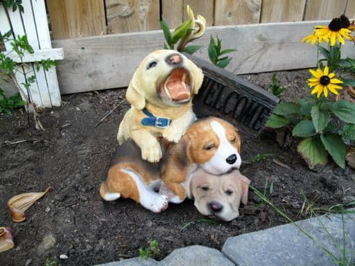 three beagle puppies statues with a Welcome sign on the flower bed