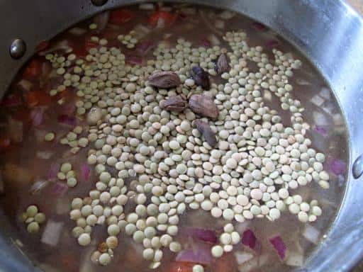 beans, lentils and cardamom pods added to the stock in the pot