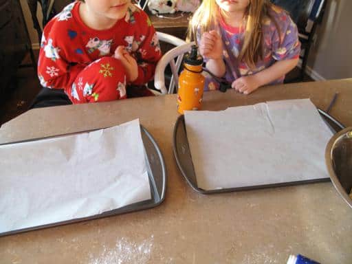 baking sheets with parchment papers in front of two kids in their pajamas