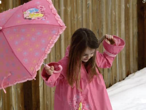 close up of a little girl wearing Disney pink coat and holding pink umbrella 