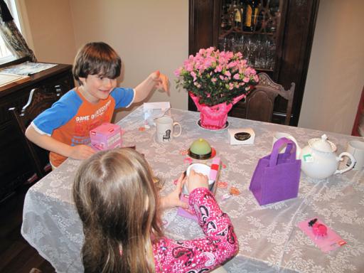 two kids enjoying the tea party inside the house while doing crafts on their mugs