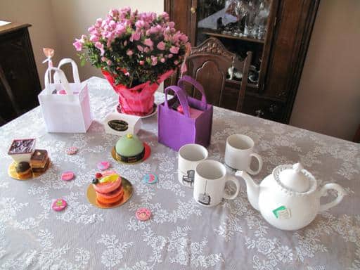 white mugs, some treats from Duchess Bakery and gift bag on tea table