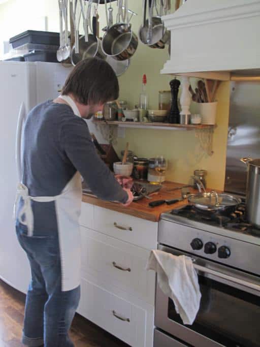 man in the kitchen wearing an apron and preparing something