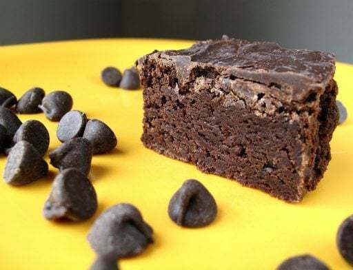 Slice of Mint Chocolate Brownies and pieces of mint chocolate chips on yellow background