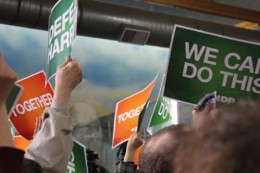 people holding green and orange signs