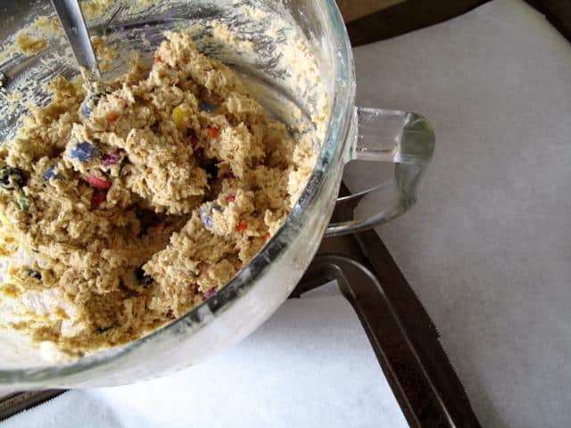 Bowl with Smartie Oatmeal Cookie dough and cookie sheet with parchment paper