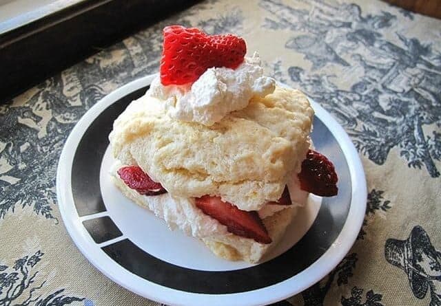 A slice of Lemon Strawberry Shortcake in a white plate with black design