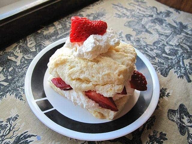 A slice of Lemon Strawberry Shortcake in a white plate with black design