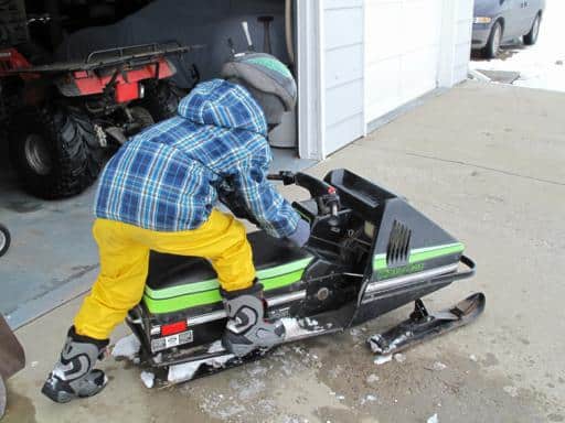 little boy learning to start his mini skidoo