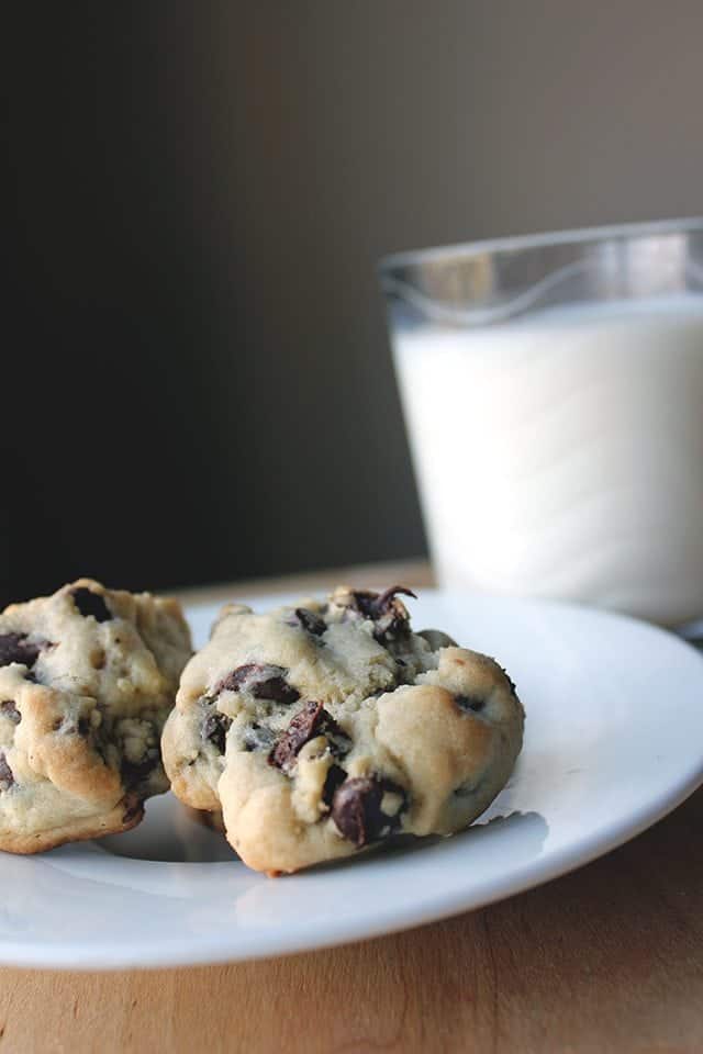 Thick & Chewy Chocolate Chip Cookies in a White plate with a Glass of milk beside it