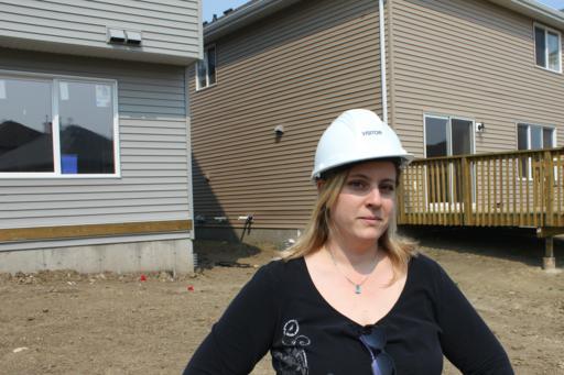 lady wearing a construction helmet, standing in front of new houses
