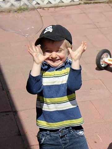 cute little boy with the bubbles popping on his face