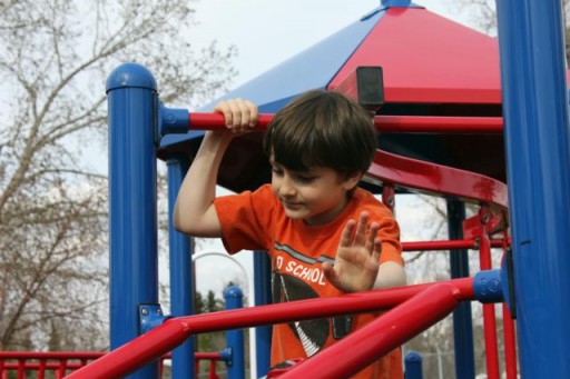 little boy enjoying the playground outside the small market