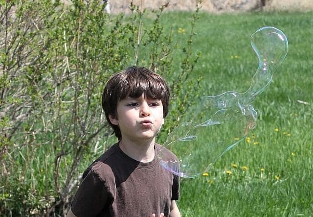 young boy enjoys blowing a bubble