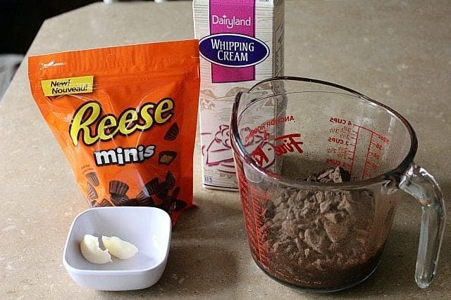 A pack of Reese's Miniature Peanut Butter Cups, whipping cream, butter in cup and chocolate in a Pyrex measuring cup