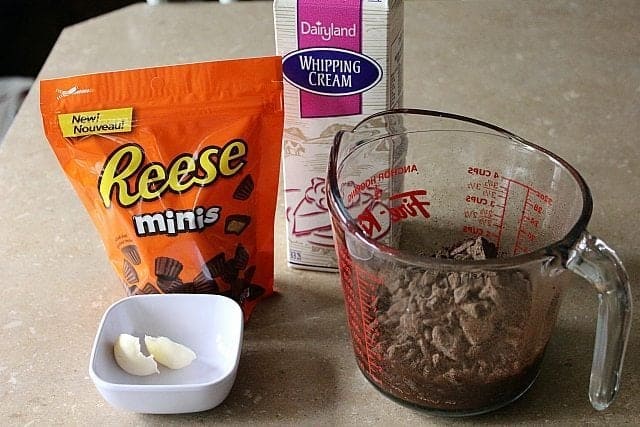 A pack of Reese's Miniature Peanut Butter Cups, whipping cream, butter in cup and chocolate in a Pyrex measuring cup