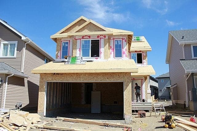 A house under construction with a man standing in front of it.