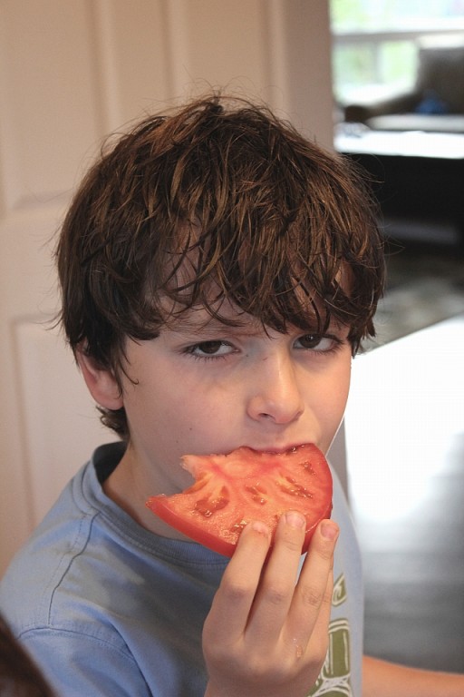 little boy eating a monster one pound tomato slice