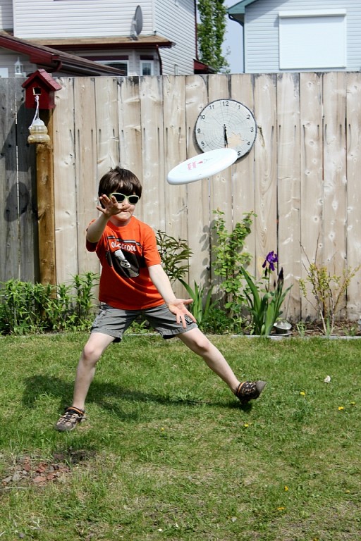 kid in orange shirt playing a frisbee