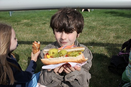 a boy enjoying his hotdog sandwich with pickles and sauerkraut