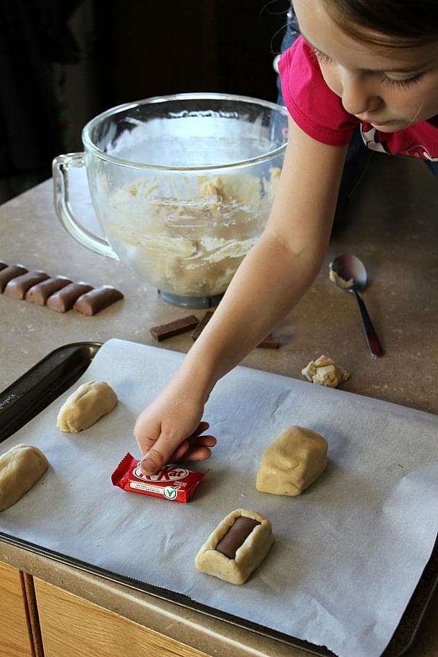 cookie dough stuffed with kitkat in a baking sheet lined with parchment paper