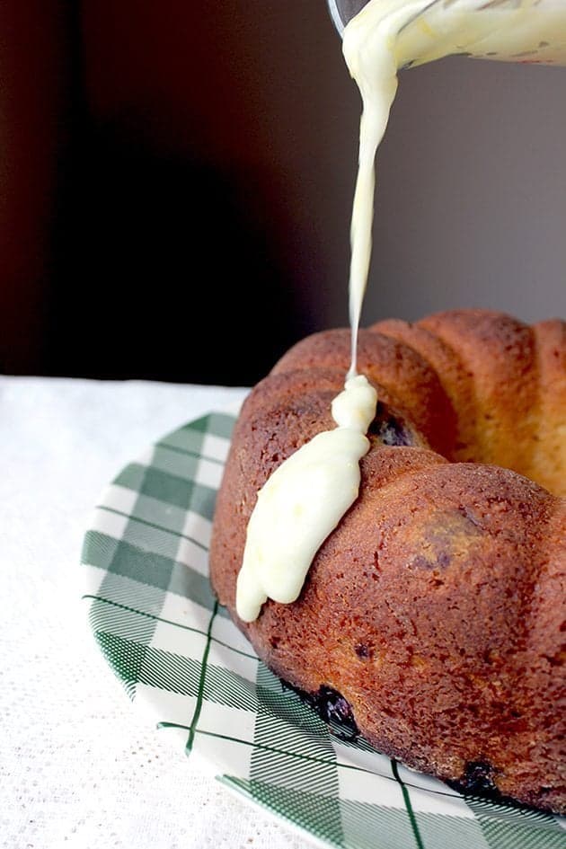 Pouring lemon glaze icing over a bundt cake