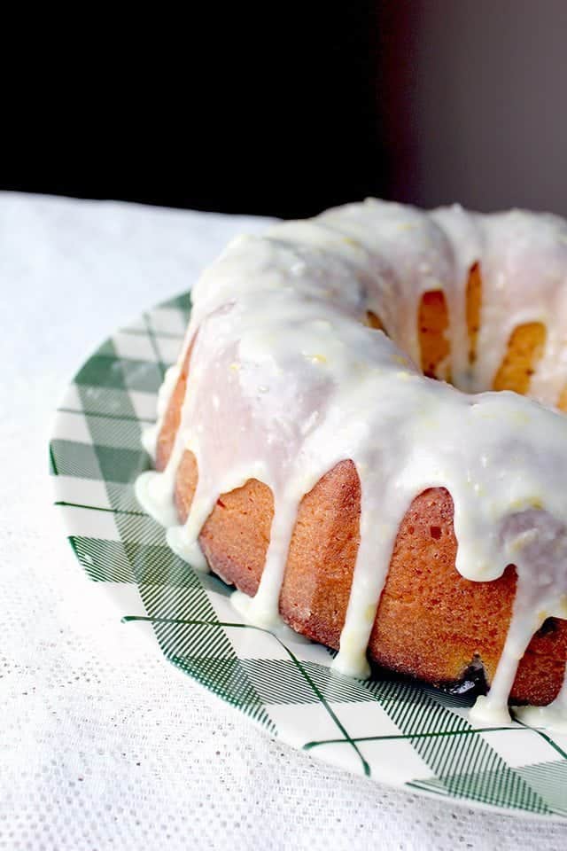 Close up of a fully iced bundt cake on a plate on a table.